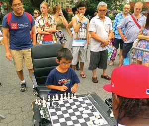 SHADES OF BOBBY FISCHER? This young lad’s performance had certainly attracted a fascinated audience. And his opponent, the regular Union Square chess player, from­the­City” was genuinely impressed, particularly when, on asking the boy’s father at the end of the game “How old is he?”—the answer that came back was “Six!” Caption Photo by Maggie Berkvist