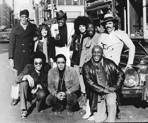 SUPER FLY CAST AND CREW MEMBERS OUTSIDE BOOMERS ON BLEECKER STREET: Included in this 1971 photo are screenwriter Phillip Fenty (bottom left), director Gordon Parks, Jr. (bottom middle), score composer Curtis Mayfield (top, second from right), and cast members Charles McGregor (bottom right), Julius Harris (top left), and Ron O’Neal (top right). Photographer unknown.