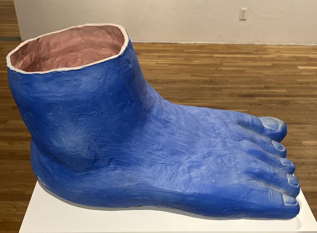 A blue foot sculpture on a white surface

Description automatically generated