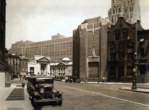 BUREAUCRATIC CREATIVITY: A subway ventilation tower built in the 1930s, generously inscribed with Art Deco decorations popular at the time, compares favorably to the MTA concrete block house erected recently on 7th Ave at the Crossing of Greenwich Avenue. The building to the right was a city library and is one of the very few buildings in New York in early Dutch architectural style. Seen behind are what was once two banks built around 1900 in what was the mandatory style for banks, classical Roman. Image courtesy of Nicola Perry.